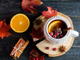 Knitted mug of traditional winter and autumn drink mulled wine or sangria on the table with dry...