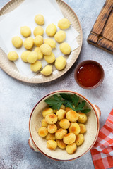 Roasted and uncooked potato gnocchi, flatlay over beige stone background, studio shot