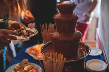 Vibrant Picture of Chocolate Fountain Fontain on a children kids birthday party with a kids playing around and dipping marshmallows and fruits into the fountain