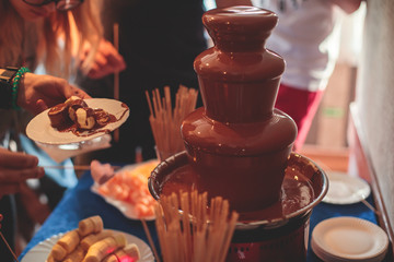 Vibrant Picture of Chocolate Fountain Fontain on a children kids birthday party with a kids playing around and dipping marshmallows and fruits into the fountain