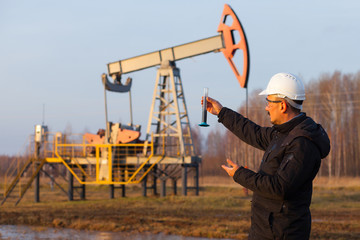 Engineer in a white helmet on an oil rig with a tablet. Oil production in Russia, Republic of Bashkortostan. Quality control. Oil production schedule