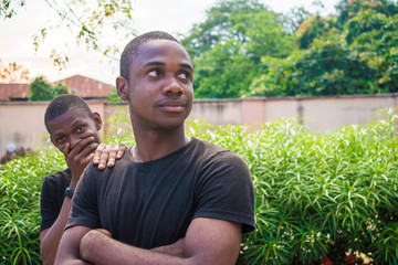 two young black male friends having a quarrel, one trying to beg the other one who feels hurt for...