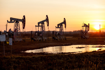 Working oil pump in rural place at sunset