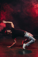 keep balance during dance, young caucasian man in smoky red background