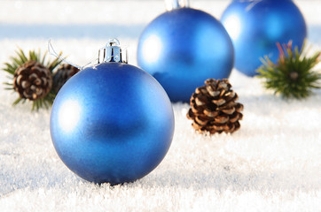 Christmas toys blue balls and a pine branch with a cone in the snow