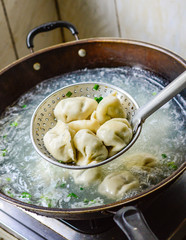 Cooking Chinese Dumplings in Boiled Water in a Wok.
