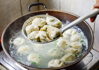 Cooking Chinese Dumplings in Boiled Water in a Wok.
