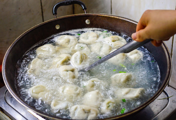 Cooking Chinese Dumplings in Boiled Water in a Wok.