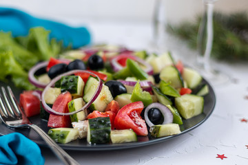 Greek salad. Diced tomatoes, cucumbers, feta cheese, olives. Rings of red onion. Food for vegetarians. Festive and New Year's dish. On a light background. Copy space. 