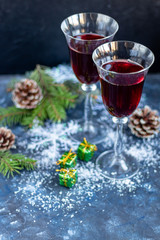 Red wine in transparent glasses. On a light background. Blurred background behind. Christmas tree branches. Copy space. 