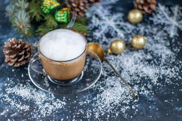 Cappuccino in a transparent cup with white, milk froth. New Year decorations, Christmas tree branches. Festive mood. Copy space. 