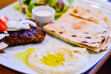 Chargrilled Minced Lamb with Hummus, Pitta Bread and Salad on White Plate. Authentic Middle Eastern Food from Restaurant