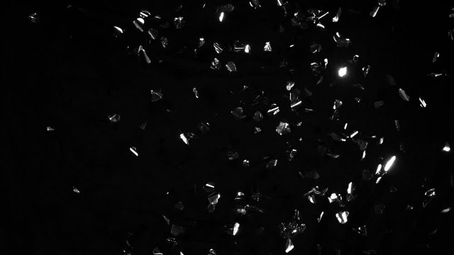 Super slow motion of flying silver confetti isolated on black background. Filmed on high speed cinema camera