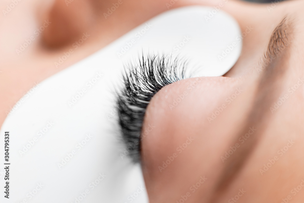 Wall mural Macro photo woman with long lashes in beauty salon. Concept eyelash extension procedure