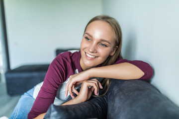 Happy young woman relaxing on comfortable soft sofa enjoying stress free weekend at home. Calm satisfied girl stretching on couch thinking of pleasant lazy day