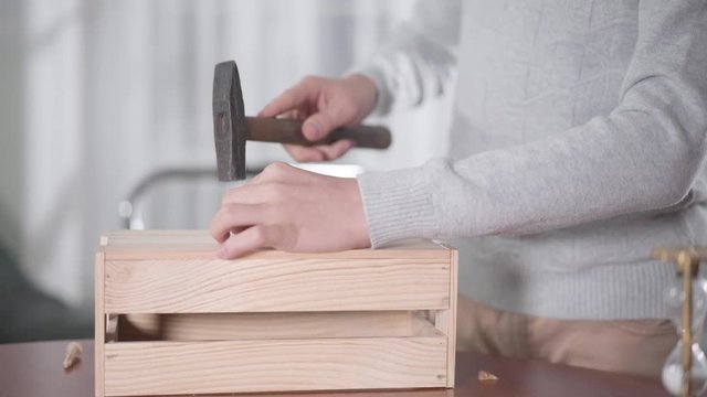 Close-up of young Caucasian man hammering nail. Young boy doing woodwork. Woodworking, carpentry for children, hobby.