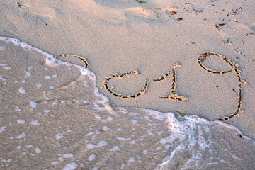 a wave erases the inscription on the sand of 2019, 2019 is ending