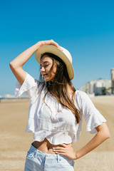 the girl in profile holds her hand on the hat, closed her eyes and with a smile of courage, she lifted her arms with her other hand