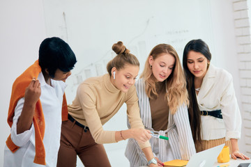 Caucasian and african female work together in office using laptop, discussing business ideas, share experience with each other. Success and leadership, togetherness concept