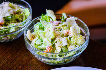 Caesar salad topped with Parmesan cheese in a glass bowl placed on table