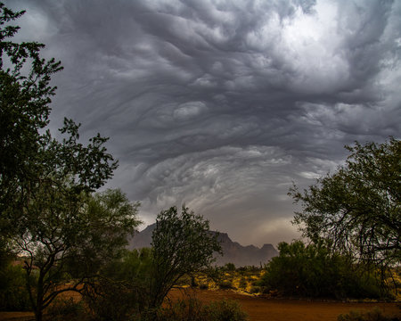 storm clouds rolling over the Superstition Mountains and kicking up a dust storm.