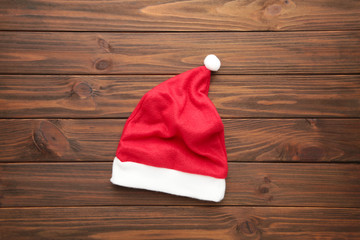 Obraz na płótnie Canvas Little Santa Claus red hat on brown wooden background