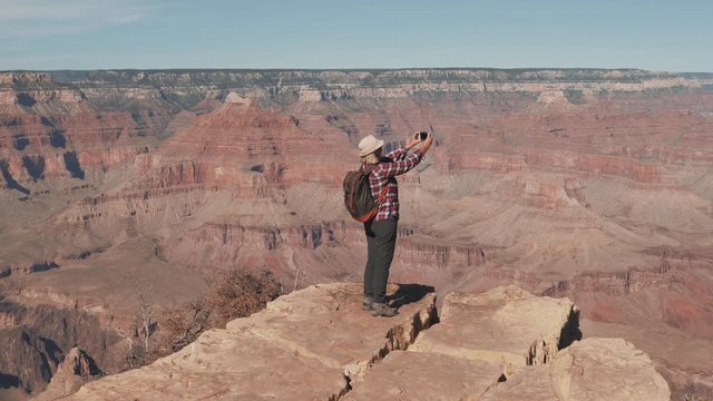 Hiker Woman Takes Photo On Smartphone Standing On Edge Of Rocks In Grand Canyon