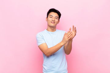 young chinese man feeling happy and successful, smiling and clapping hands, saying congratulations...