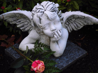 träumender Engel mit roter Rose auf dem Friedhof
