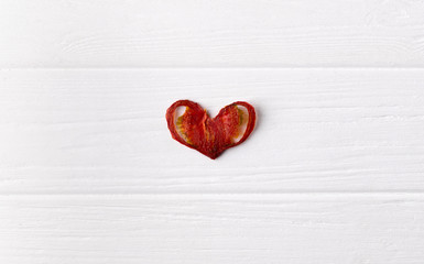 Crisp crunchy organic tomato chips in heart shape on a white wooden background