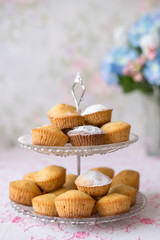 dish glass bunk with cupcakes on the background of a bouquet of blurred