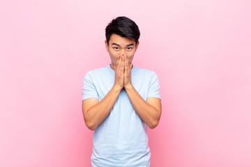 young chinese man happy and excited, surprised and amazed covering mouth with hands, giggling with...