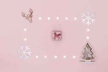 New Year and Christmas composition. Frame from white stars, snowflakes, chrismas tree and gift box on pastel pink background. Top view, flat lay, copy space.