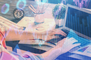 Double exposure of stock graph with businessman typing on computer in office on background. Concept of hard work.