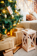 Christmas interior of the living room - a bright room with New Year's decoration - Christmas trees, gift boxes, a fireplace with candles, decorated with a pine garland with toys. New year interior