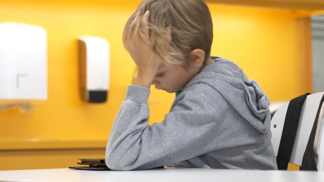 Tired elementary school boy reading on a tablet, Static medium shot
