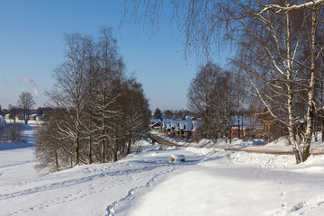 Fototapeta na wymiar wooden houses stand along the road, winter landscape