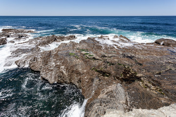 Rebentação das ondas do oceano no rochedo da costa.