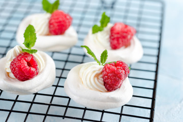 Mini Pavlova meringue with whipped cream and raspberries.
