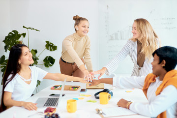 attractive diverse female joined hands as team, coworking of creative people in office