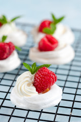 Mini Pavlova meringue with whipped cream and raspberries.