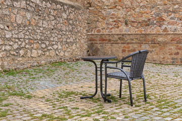Fototapeta na wymiar Metal chair and table near old ancient walls of the Tetouan Medina (Northern Morocco) in historical center of the city.
