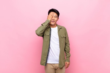 young chinese man laughing and slapping forehead like saying d‚Äôoh! I forgot or that was a...