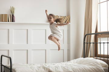 Fototapeta na wymiar Happy preschooler girl jump high relaxing in bedroom
