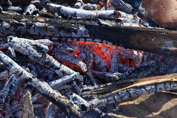 Red-hot smoldering bonfire from wooden branches and twigs.