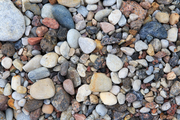 Pile of different smooth stones on the seashore.