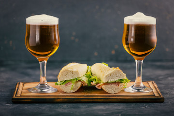 Two glasses of beer with foam and delicious sandwiches in a pub.
