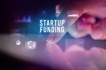 Finger touching tablet with charts and STARTUP FUNDING inscription, business concept