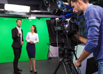 Fototapeta na wymiar Presenters and video camera operator working in studio. News broadcasting