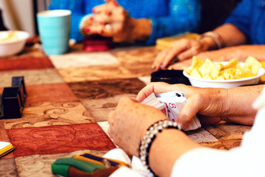 Close up of senior women's hands playing cards at table